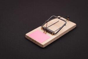 Blank Pink Sheet of Paper in Wooden Mousetrap - Template. Small Memo Paper in Mouse Trap on Black Background photo