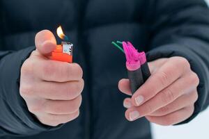 Guy Sets Fire to the Flash Noise Firecrackers Outdoors in Winter at Daytime. Loud and Dangerous New Year's Entertainment. Hooliganism with Pyrotechnics. Noise of Petards in Public Places photo