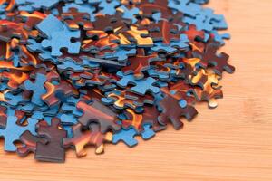 Colorful Pieces of a Mixed Jigsaw Puzzle Lie on the Wooden Table - Strategy and Solving Problem Concept photo
