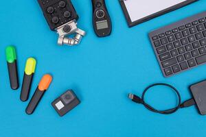 Top View of Photographer's, Videographer's or Blogger's Workplace. Digital Gadgets Lying on Blue Table - Flat Lay photo