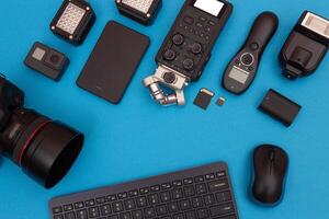 Top View of Photographer's, Videographer's or Blogger's Workplace. Digital Gadgets Lying on Blue Table - Flat Lay photo