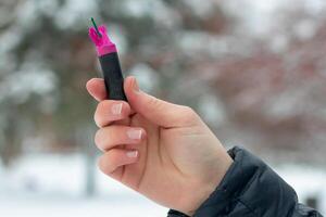 Firecracker in a Hand. Guy Holding a Petard Outdoors in Winter at Daytime. Loud and Dangerous New Year's Entertainment. Hooliganism with Pyrotechnics. Noise of Firecrackers in Public Places photo