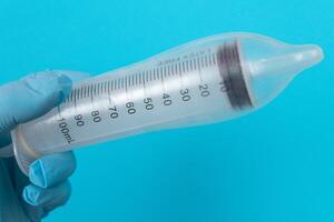 Safe Vaccine, Anti Vaccination Concept - Syringe in a Condom Holds in a Hand with Medical Glove. Mistrust of Vaccination. Natural Immunity. Skepticism About the Vaccine. Freedom and Human Rights photo