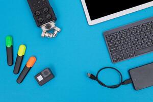 Top View of Photographer's, Videographer's or Blogger's Workplace. Digital Gadgets Lying on Blue Table - Flat Lay photo