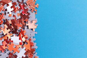 Mixed Pieces of a Colorful Jigsaw Puzzle Lie on the Blue Background With Copy Space - Strategy and Solving Problem Concept photo
