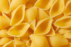 Uncooked Conchiglie Pasta. A Culinary Canvas of Conchiglie Macaroni, Creating a Lively and Textured Background for Gourmet Cooking. Dry Pasta. Raw Macaroni - Top View, Flat Lay photo