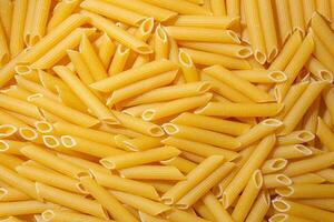 Uncooked Penne Rigate Pasta. A Culinary Canvas of Penne Macaroni, Creating a Lively and Textured Background for Gourmet Cooking. Dry Pasta. Raw Macaroni - Top View, Flat Lay photo