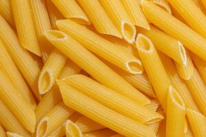 Uncooked Penne Rigate Pasta. A Culinary Canvas of Penne Macaroni, Creating a Lively and Textured Background for Gourmet Cooking. Dry Pasta. Raw Macaroni - Top View, Flat Lay photo