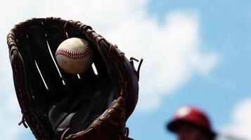 baseball glove catches ball against bright blue sky, capturing excitement of game. scene evokes sense of anticipation and joy in sports photo