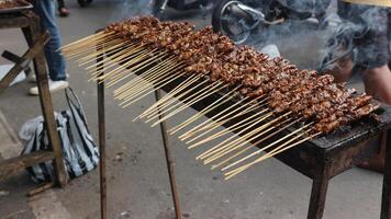 Satay goat satay, lamb, lamb or meat goat satay in grilling place with smoke by people with yummy looking. traditional satay from java, Indonesia. photo