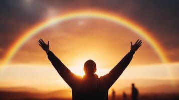 person stands with arms raised in front of vibrant rainbow during sunset, symbolizing joy and hope. scene captures moment of tranquility and connection with nature photo