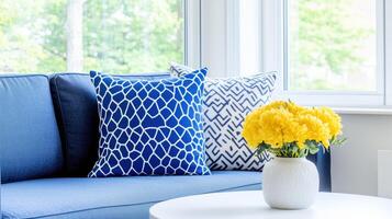 Brighten your living space with cozy blue sofa adorned with patterned cushions and vibrant bouquet of yellow flowers in modern vase. This inviting setup creates cheerful atmosphere photo