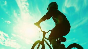 silhouette of cyclist riding bike against vibrant sky, capturing sense of freedom and adventure. sun shines brightly, creating dramatic backdrop photo