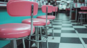 Retro diner seating with pink stools and checkered floor creates nostalgic atmosphere. vibrant colors and classic design evoke sense of warmth and comfort photo