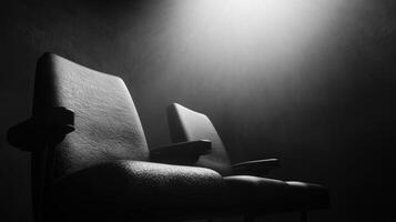 Two black chairs in dimly lit space create dramatic atmosphere, evoking sense of mystery and anticipation. shadows enhance mood of scene photo