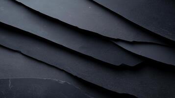 Textured layers of dark slate create striking visual effect, showcasing natural beauty and depth of material. smooth surfaces and sharp edges evoke sense of elegance and sophistication photo