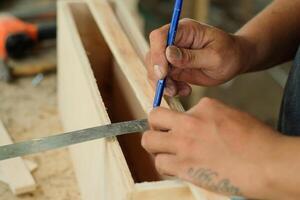 Carpenter is measuring a product with ruler photo