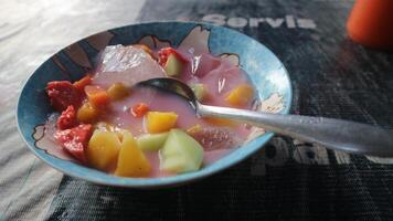 sop buah or fruit soup is indonesian fruit cocktail ice made from various diced fruits mixed with ice cubes, condensed milk and red syrup. popular for buka puasa break fasting. selected focus photo