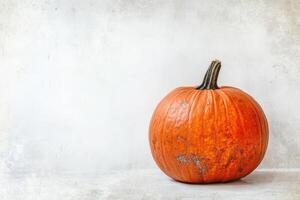 A Single Orange Pumpkin Resting on a White Surface photo