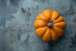 A Single Orange Pumpkin on a Weathered Grey Surface photo