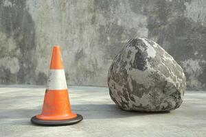 Orange Traffic Cone and Large Grey Rock on Concrete photo