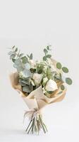Elegant bouquet of white roses and eucalyptus beautifully wrapped in paper. Professional florist photo