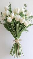 Elegant white tulip bouquet tied with twine on white background, natural beauty and simplicity photo
