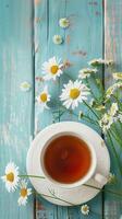 Cup of chamomile tea with fresh flowers on rustic blue wooden background, relaxing and wellness vibe photo