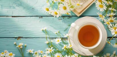 Cup of chamomile tea with fresh flowers on rustic blue wooden background, relaxing and wellness vibe photo