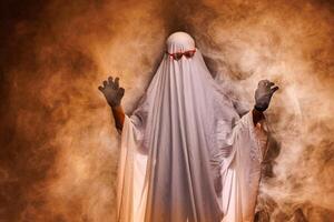 man in scary ghost costume in smoke on grey mysterious background in studio. Minimal halloween ghost concept. photo