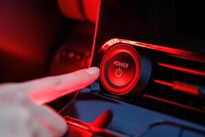 Hand pressing power button on modern black dashboard, event activation concept photo