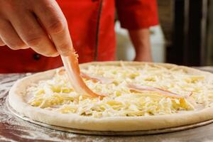 Chef adding bacon to cheese pizza photo