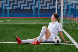 Football player sitting on the grass of a football field, break after a football match photo