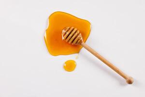 honey spoon with spilled honey on white background, top view photo