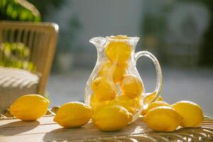 A pitcher of lemonade with sliced lemons and oranges on a table photo