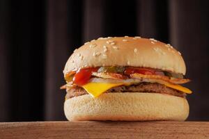 A delicious cheeseburger with bacon, sesame, layers of cheese, pickles, onions and sauces photo