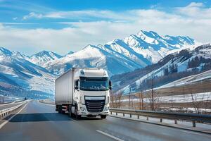 A truck driving down a road with snow covered mountains in the background photo