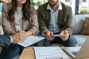 A man and woman are sitting on a couch with a laptop and papers photo