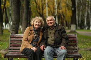 An elderly couple sitting on a bench in a park photo