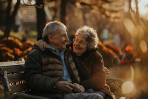 An elderly couple sitting on a bench in a park photo