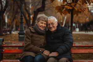 An older couple sitting on a bench in a park photo
