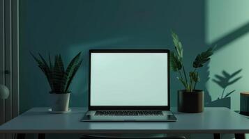 A laptop sitting on a desk with a plant in front of it photo