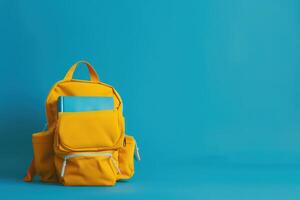 A yellow backpack with a blue notebook on a blue background photo