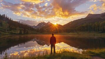 A man standing in front of a lake at sunset photo