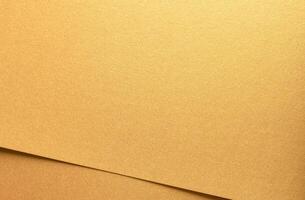 Golden metallic paper with a glossy texture and layered folds. The rich, warm surface shines with photo