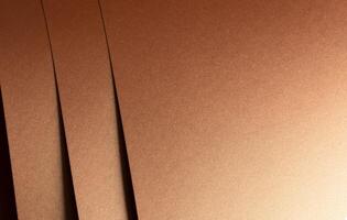 Copper metallic texture with layered folds and a smooth, reflective surface. Geometric lines and photo
