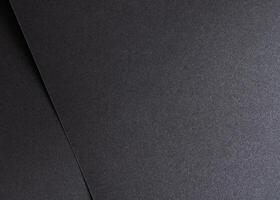 Black paper background with a smooth, dark texture, creating a grunge and modern aesthetic. Blank photo