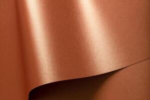 Copper metallic texture with glossy, reflective folds. Designer paper with a smooth, shiny surface photo