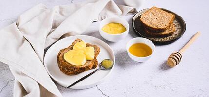 Morning sandwiches on grain bread with honey butter on a plate on the table web banner photo