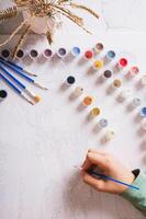 A girl paints a picture by numbers with a brush using a paint set top and vertical view photo
